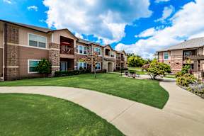 Timber Creek Apartments in Sulphur Springs, TX featuring landscaped walkways and apartment homes