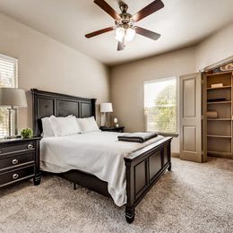 a bedroom with a large bed and a ceiling fan at Cypress Creek Apartments