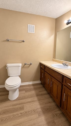 A white toilet sits in a bathroom with wooden floors and brown walls.