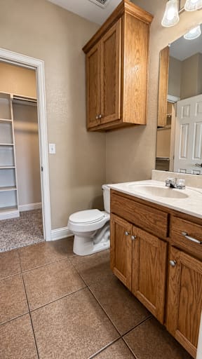 A bathroom with a white toilet and wooden cabinets.