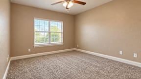 A room with a ceiling fan and a window with blinds.