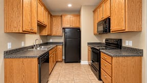 A kitchen with wooden cabinets and black appliances.