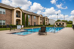 A pool area in front of a brick apartment building.