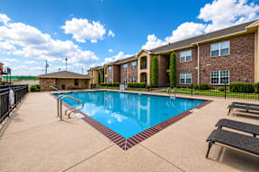 A pool surrounded by a black fence and a building in the background.