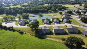 an aerial view of a neighborhood with houses and a pond