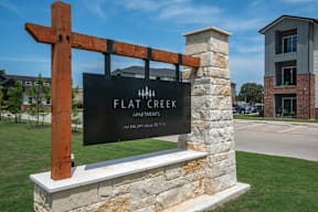 A sign for Flat Creek Apartments is displayed in front of a building.