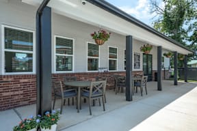 A patio at Flat Creek Apartments with a table and chairs is covered by a roof.