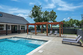 Flat Creek Apartments pool with a slide and a wooden pergola.