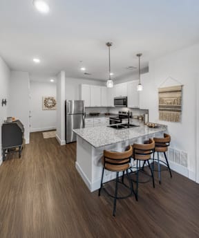 A modern kitchen with a white island and brown bar stools.