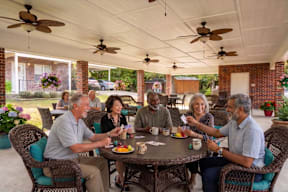 A group of people are sitting around a table playing a card game.