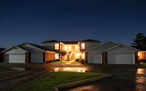 A house with a garage is illuminated from the inside.