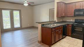Apartment kitchen with wood cabinetry and black appliances at Timber Creek Apartments