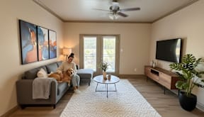 Resident relaxing with a dog in a furnished apartment at Timber Creek Apartments