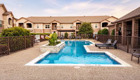 Resort-style swimming pool with lounge seating at Timber Creek Apartments