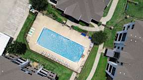 A swimming pool surrounded by a grassy area and apartment buildings.