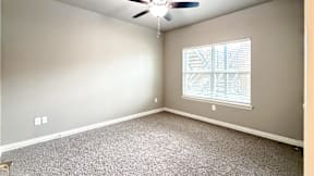 A room with a ceiling fan and a window with blinds.