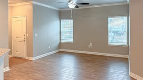 A room with a ceiling fan and two windows.