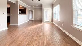 A spacious room with wooden flooring and a ceiling fan.