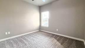 A room with a carpeted floor and a window letting in sunlight.