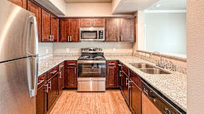 A kitchen with wooden cabinets and a stainless steel refrigerator.