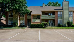 an apartment building with a parking lot in front of it