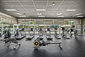 A gym with a row of treadmills and elliptical machines.