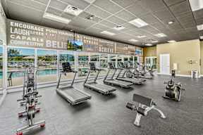 A gym with a variety of equipment including treadmills, elliptical machines, and weights.