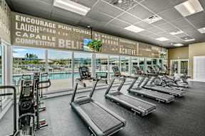 A gym with treadmills and a wall of motivational words.