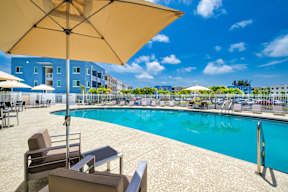 A sunny day at the pool with chairs and umbrellas.