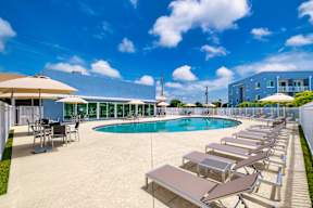 A large outdoor swimming pool with sun loungers and umbrellas.