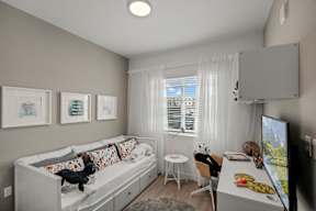 A modern bedroom with a bed, desk, and television.