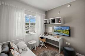 A living room with a white couch, a white chair, a white desk, and a white teddy bear.