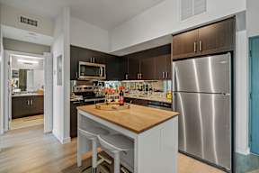 A modern kitchen with a wooden island and stainless steel appliances.