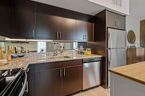 A modern kitchen with dark brown cabinets and stainless steel appliances.