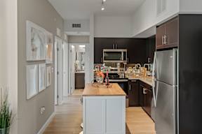 A modern kitchen with a black refrigerator and wooden countertops.