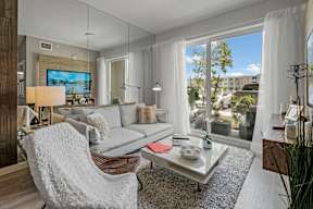 A modern living room with a grey sofa, a white chair, and a television.