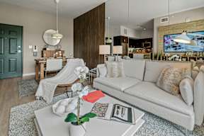 A living room with a white couch and a coffee table with a vase of flowers on it.
