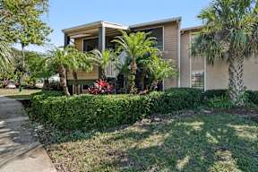 A house with a green lawn and trees in front.