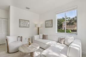 A living room with a white couch, a coffee table, and two chairs.