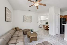 A living room with a brown couch and a ceiling fan.