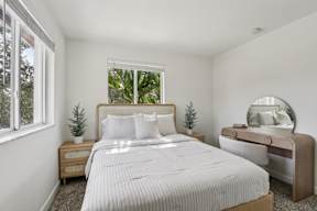 A bedroom with a large bed, a nightstand, and a mirror.