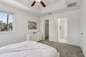 A bedroom with a bed, dresser, and a painting on the wall.