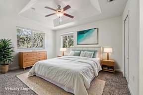 A bedroom with a bed, nightstand, and a ceiling fan.