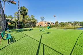 A green park with a playground and a building in the background.