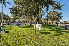 A park with a white circular sign in the middle of the grass.
