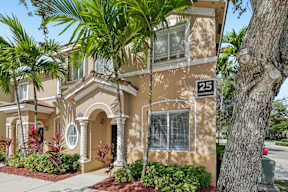 A beige house with a tree in front.