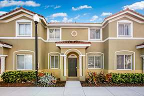 a beige house with a sidewalk in front of it