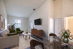 A living room with a couch, chairs, a coffee table, and a television.