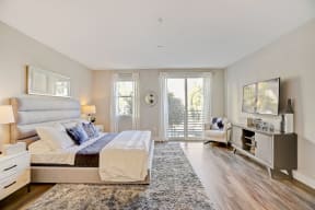 Cozy bedroom featuring a comfortable bed, flat-screen TV, and door leading to a private balcony