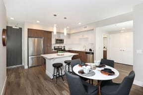 Open-concept kitchen and dining area featuring stainless steel appliances and a sleek white dining table.